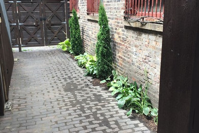 This is an example of a small country courtyard partial sun formal garden for summer in Chicago with a garden path and brick pavers.