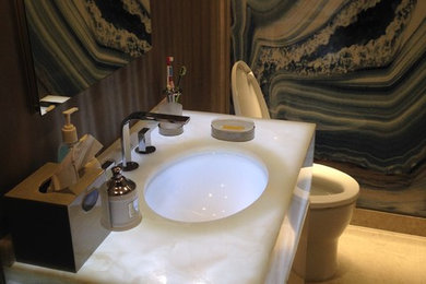 Mid-sized trendy master white tile, black tile and marble tile ceramic tile and beige floor bathroom photo in New York with flat-panel cabinets, dark wood cabinets, a one-piece toilet, brown walls, a wall-mount sink and onyx countertops