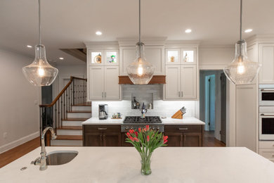 Medium tone wood floor kitchen photo in Atlanta with an undermount sink, shaker cabinets, quartz countertops, white backsplash, porcelain backsplash, stainless steel appliances, an island and white countertops
