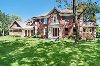 Inspiration for a large timeless red two-story brick exterior home remodel in Chicago