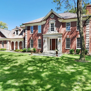 Exempel på ett stort klassiskt rött hus, med tegel och två våningar