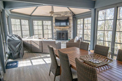 Example of a large farmhouse vinyl floor and brown floor sunroom design in Louisville with a wood stove and a stacked stone fireplace