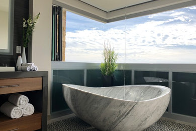 Freestanding bathtub - large contemporary master black tile and stone tile pebble tile floor and black floor freestanding bathtub idea in Orange County with flat-panel cabinets, medium tone wood cabinets, white walls, a vessel sink and quartz countertops