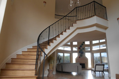 Mid-sized contemporary wood curved staircase in Houston with wood risers and metal railing.