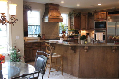 Open concept kitchen - mid-sized transitional l-shaped ceramic tile and beige floor open concept kitchen idea in Chicago with an undermount sink, raised-panel cabinets, medium tone wood cabinets, marble countertops, beige backsplash, ceramic backsplash, stainless steel appliances and an island