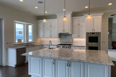 Example of a huge minimalist u-shaped porcelain tile and brown floor open concept kitchen design in Other with an undermount sink, raised-panel cabinets, white cabinets, granite countertops, white backsplash, cement tile backsplash, stainless steel appliances, an island and gray countertops
