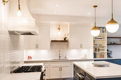 Inspiration for a large transitional l-shaped open plan kitchen in Toronto with an undermount sink, shaker cabinets, white cabinets, quartz benchtops, white splashback, porcelain splashback, stainless steel appliances, medium hardwood floors, with island, brown floor and white benchtop.