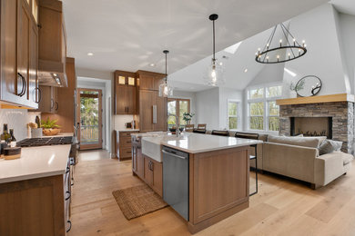 Example of a huge transitional u-shaped light wood floor, brown floor and vaulted ceiling eat-in kitchen design in Portland with a farmhouse sink, shaker cabinets, medium tone wood cabinets, quartz countertops, white backsplash, ceramic backsplash, stainless steel appliances, an island and white countertops