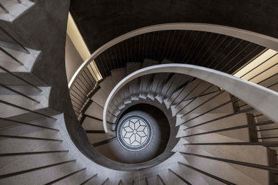 Medium sized contemporary concrete spiral metal railing staircase spindle in London with concrete risers and wainscoting.