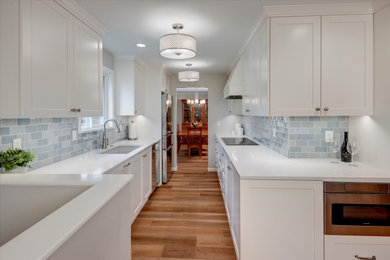 This is an example of a small galley kitchen/diner in Seattle with a submerged sink, engineered stone countertops, blue splashback, ceramic splashback, stainless steel appliances, light hardwood flooring, no island, brown floors and white worktops.