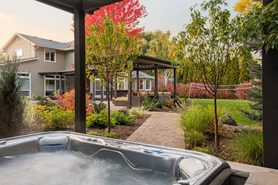 Photo of a large contemporary backyard pool in Boise with brick pavers and a hot tub.