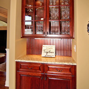 Mid-sized traditional kitchen pantry ideas - Kitchen pantry - mid-sized traditional single-wall medium tone wood floor kitchen pantry idea in Indianapolis with glass-front cabinets, medium tone wood cabinets, granite countertops, brown backsplash and stainless steel appliances