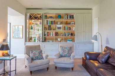 Photo of a traditional formal open plan living room in Edinburgh with medium hardwood flooring, a two-sided fireplace, a plastered fireplace surround, a wall mounted tv, brown floors and feature lighting.