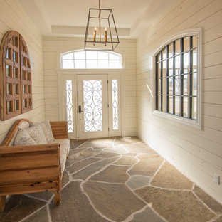 Réalisation d'un grand hall d'entrée bohème avec un sol en ardoise, une porte simple, une porte blanche et un sol multicolore.