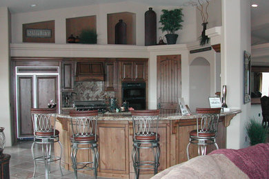 Kitchen - transitional u-shaped travertine floor kitchen idea in Phoenix with raised-panel cabinets, dark wood cabinets, granite countertops, beige backsplash, stone tile backsplash, paneled appliances and an island