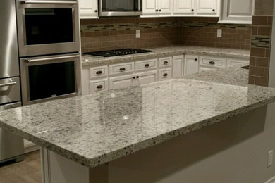 Example of a transitional u-shaped medium tone wood floor eat-in kitchen design in San Diego with an island, raised-panel cabinets, white cabinets, granite countertops, brown backsplash and stone tile backsplash