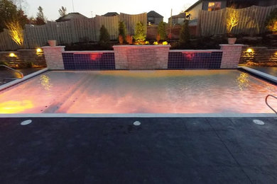 Example of a mid-sized transitional backyard stamped concrete and rectangular pool fountain design in Other