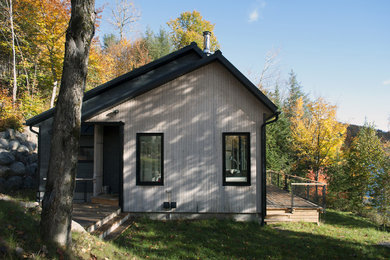 Photo of a small scandinavian one-storey grey house exterior in Montreal with wood siding, a shed roof and a metal roof.