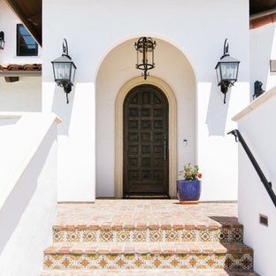 サンルイスオビスポの片開きドア地中海スタイルのおしゃれな玄関ドア (白い壁、レンガの床、濃色木目調のドア、赤い床) の写真