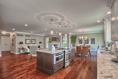 Example of a mid-sized classic single-wall medium tone wood floor open concept kitchen design in St Louis with an undermount sink, recessed-panel cabinets, white cabinets, granite countertops, gray backsplash, stone tile backsplash, stainless steel appliances and an island