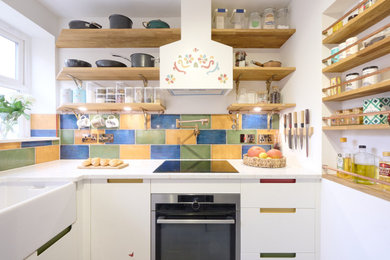 Photo of a small contemporary galley enclosed kitchen in London with a belfast sink, flat-panel cabinets, white cabinets, quartz worktops, multi-coloured splashback, porcelain splashback, stainless steel appliances, porcelain flooring, no island, grey floors and multicoloured worktops.