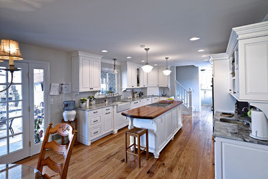 Inspiration for a mid-sized farmhouse galley medium tone wood floor enclosed kitchen remodel in Philadelphia with shaker cabinets, white cabinets, wood countertops, an island and a farmhouse sink