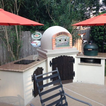 Brick pizza oven in outdoor kitchen with ceramic kamado grill