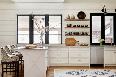 Example of a mid-sized country medium tone wood floor and brown floor kitchen design in Atlanta with white cabinets, stainless steel appliances, a peninsula, an undermount sink, marble countertops, white backsplash, white countertops and beaded inset cabinets