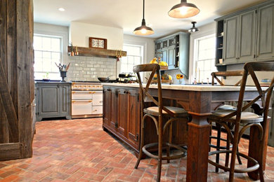 Example of a large country l-shaped brick floor and red floor enclosed kitchen design in Philadelphia with raised-panel cabinets, gray cabinets, marble countertops, gray backsplash, subway tile backsplash, white appliances and an island