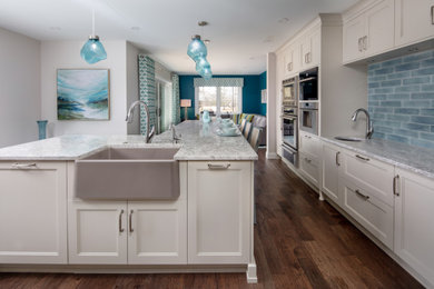 Large eclectic galley medium tone wood floor and brown floor open concept kitchen photo in Toronto with a farmhouse sink, shaker cabinets, white cabinets, quartz countertops, blue backsplash, porcelain backsplash, stainless steel appliances, an island and gray countertops