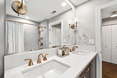 This is an example of a mid-sized transitional kids bathroom with shaker cabinets, grey cabinets, an alcove tub, a shower/bathtub combo, a two-piece toilet, blue tile, subway tile, grey walls, cement tiles, an undermount sink, quartzite benchtops, white floor, a shower curtain, white benchtops, a double vanity and a built-in vanity.