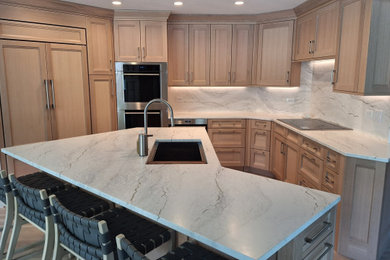 Inspiration for a mid-sized timeless u-shaped light wood floor open concept kitchen remodel in Chicago with an undermount sink, recessed-panel cabinets, light wood cabinets, quartz countertops, white backsplash, stone slab backsplash, paneled appliances, an island and white countertops