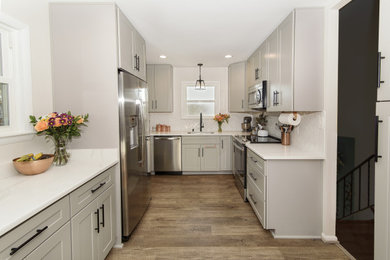 Bild på ett litet vintage vit vitt kök, med en undermonterad diskho, skåp i shakerstil, grå skåp, bänkskiva i kvarts, vitt stänkskydd, stänkskydd i tunnelbanekakel, rostfria vitvaror, vinylgolv och brunt golv