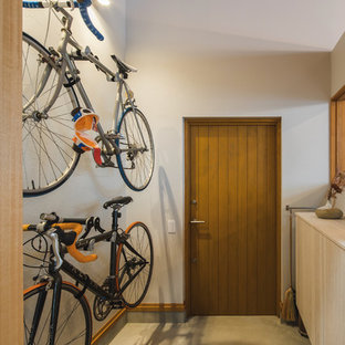 大阪の片開きドアミッドセンチュリースタイルのおしゃれな玄関ホール (白い壁、コンクリートの床、木目調のドア、グレーの床) の写真