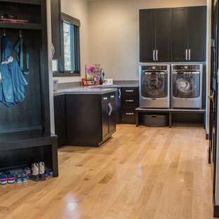 Design ideas for a medium sized modern u-shaped utility room in Other with a submerged sink, shaker cabinets, black cabinets, granite worktops, beige walls, light hardwood flooring, a side by side washer and dryer and brown floors.