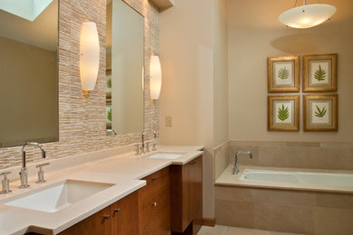 Mid-sized contemporary master bathroom in Boston with flat-panel cabinets, medium wood cabinets, a drop-in tub, beige tile, stone tile, beige walls, an undermount sink and solid surface benchtops.