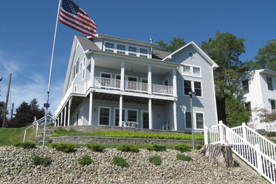 This is an example of a mid-sized beach style two-storey grey exterior in New York with vinyl siding and a gable roof.