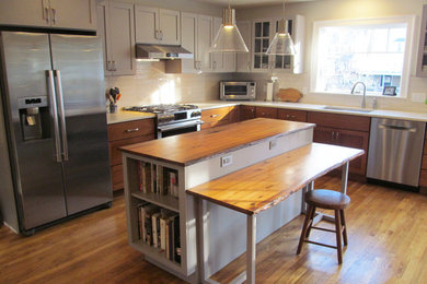 Inspiration for a mid-sized transitional l-shaped medium tone wood floor and brown floor eat-in kitchen remodel in Boston with shaker cabinets, gray cabinets, wood countertops, white backsplash, subway tile backsplash, stainless steel appliances, an island and brown countertops