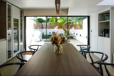 Inspiration for a large classic dining room in London with white walls, brown floors, a wallpapered ceiling, panelled walls and feature lighting.