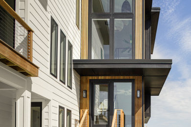 Modelo de fachada de casa negra minimalista de tamaño medio de tres plantas con revestimiento de madera, tejado plano y tablilla