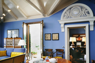 ヴェネツィアにある高級な中くらいなエクレクティックスタイルのおしゃれなLDK (青い壁、淡色無垢フローリング、標準型暖炉、石材の暖炉まわり、表し梁) の写真