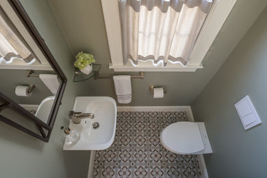Photo of a small transitional bathroom in Boston with a wall-mount toilet, green walls, cement tiles, a wall-mount sink and multi-coloured floor.