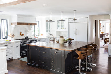 Large trendy u-shaped brown floor and dark wood floor eat-in kitchen photo with a farmhouse sink, white cabinets, wood countertops, white backsplash, an island, white countertops, shaker cabinets and white appliances