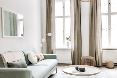 Geräumiges, Offenes Nordisches Wohnzimmer mit braunem Holzboden, freistehendem TV und braunem Boden in Berlin