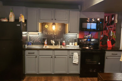 Example of a mid-sized urban walk-out laminate floor and brown floor basement design in Grand Rapids with beige walls, a standard fireplace and a brick fireplace