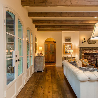 Großes, Offenes Mediterranes Wohnzimmer mit beiger Wandfarbe, braunem Holzboden, Kamin, Kaminsims aus Holz und Wand-TV in Houston