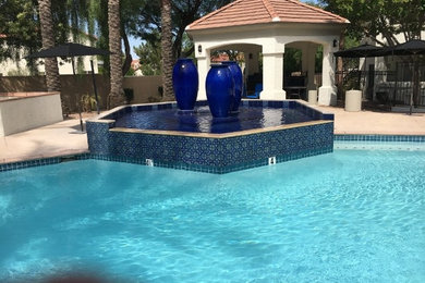 Imagen de piscina con fuente natural grande a medida en patio trasero con losas de hormigón