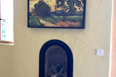 Photo of a mid-sized mediterranean master bedroom in San Francisco with beige walls, medium hardwood floors, a standard fireplace, a metal fireplace surround and brown floor.