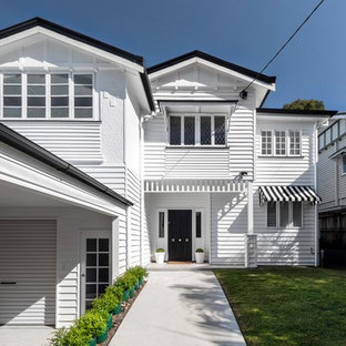 Country two-storey white house exterior in Brisbane with a gable roof, vinyl siding and a metal roof.