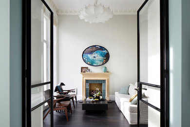 Photo of a contemporary enclosed living room in London with white walls, a standard fireplace and a tile fireplace surround.